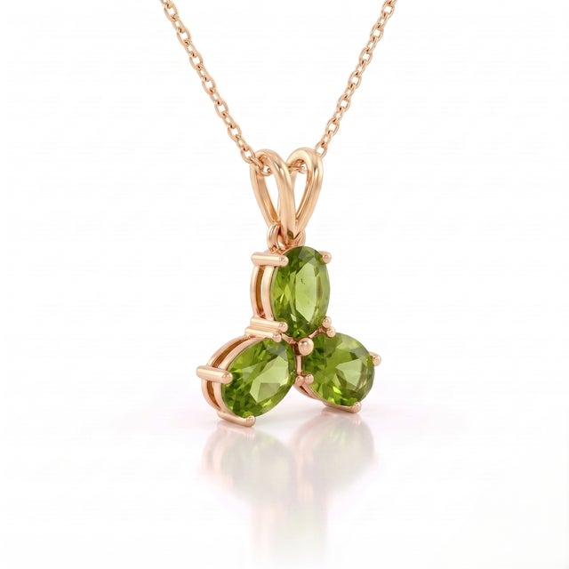A vibrant three-stone design featuring oval-cut natural peridots arranged in a graceful trefoil formation, secured in a...