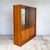 A glazed bookcase and display cabinet by herbert gibbs, made from veneered board. The sides, top and display floor show a...