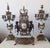 An elegant Lancini clock with a pair of Louis XVI-style candlesticks, crafted from bronze and white marble with exquisite...