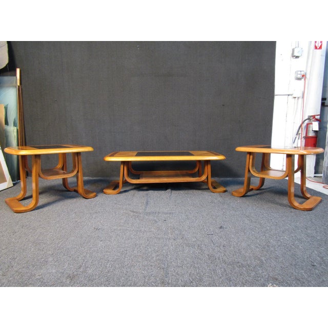 This unique coffee table set includes one wide coffee table and two smaller side tables. A unique design includes dark...