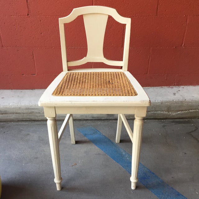 A unique cream colored French accent chair with a cane seat.
