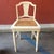 A unique cream colored French accent chair with a cane seat.