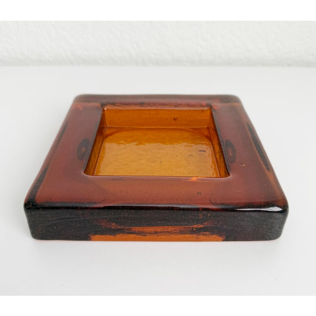 Brutalist style, thick art glass ashtray or catchall in the style of Blenko Glass. It is a deep amber/copper color and...