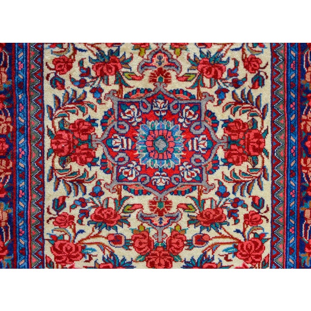 A wonderful boldly patterned rug with large-scale flowers and leaves woven in reds, pinks, greens, all against a cream...