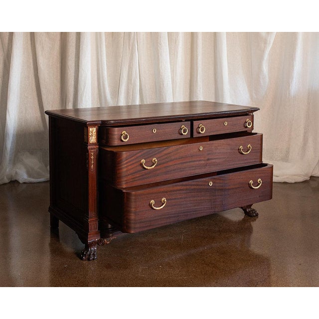 This antique French mahogany chest of drawers boasts rich, flowing grain patterns and ornate brass hardware that highlight...