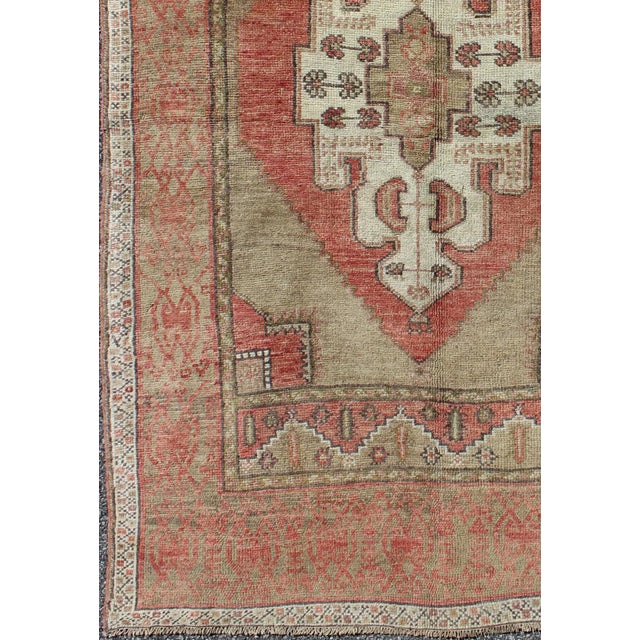 This vintage Turkish Oushak rug features an intricately beautiful design with a tribal aesthetic. The central medallion is...