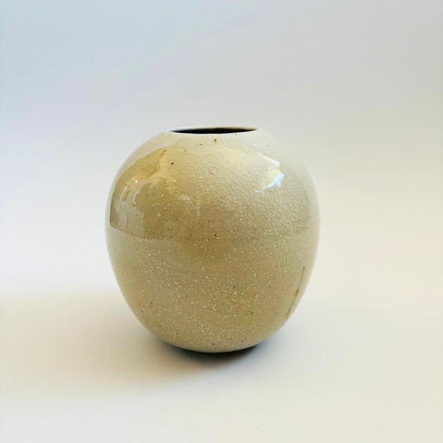 A vintage studio pottery vase in a tall sphere shape. Beautiful cream crackle glaze with a few small speckles. Signed on...