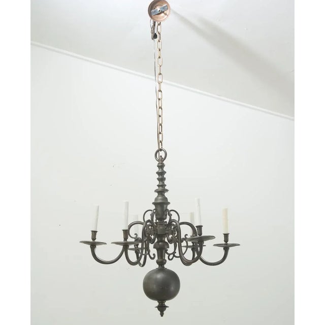 A large, antique six light brass chandelier heavily patinated to a gunmetal gray that will make an eye-catching statement...