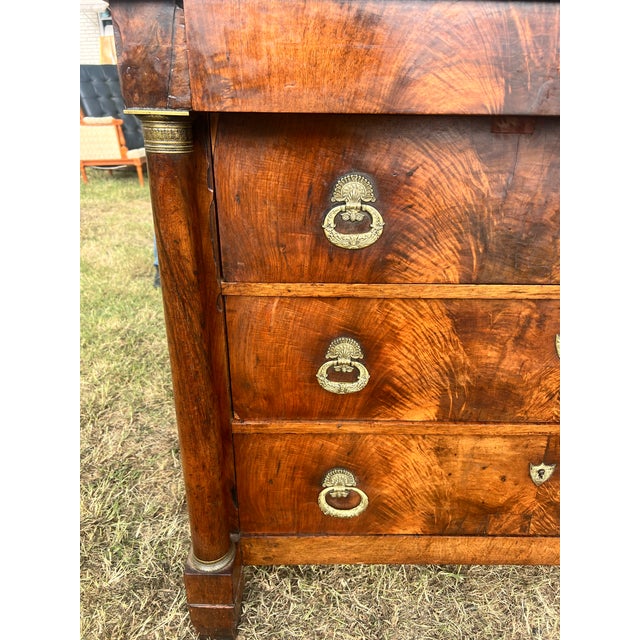 An elegant 19th-century French Empire commode crafted in richly figured flame mahogany veneer. Featuring three spacious...