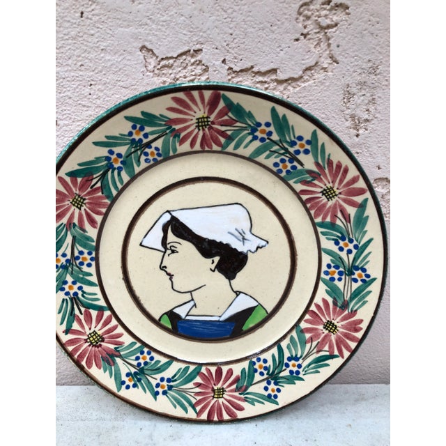 French faience plate Quimper, circa 1920 Border with flowers, representing a woman with a traditional Brittany cap.