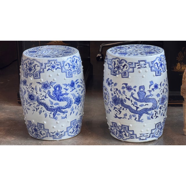 Pair of blue and white porcelain garden stools of barrel form, painted with striding dragons among flowering branches...
