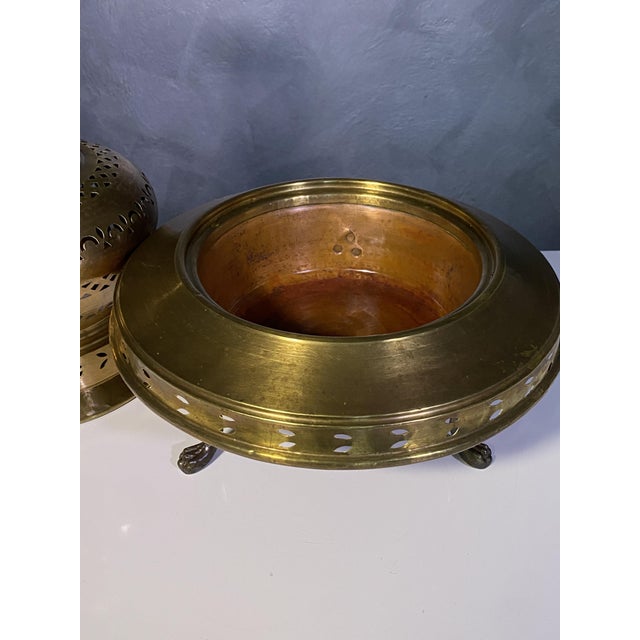 Antique copper and brass brazier divided into two parts, with a decorative top, mounted on three finely decorated legs. It...