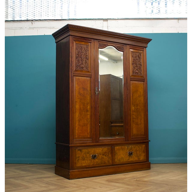 A well-proportioned late Victorian wardrobe or hall cupboard in warm walnut, featuring burr walnut panels, carved foliate...
