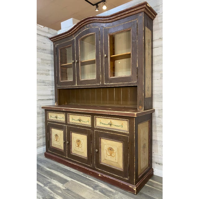 Large European china hutch with rustic charm and hand painted floral details. The wood shows natural distressing and a...