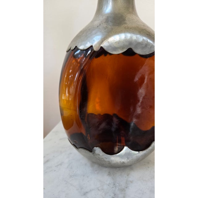A distinctive vintage Dutch decanter by Royal Holland Daalderop, combining warm amber glass with sculptural pewter mounts....