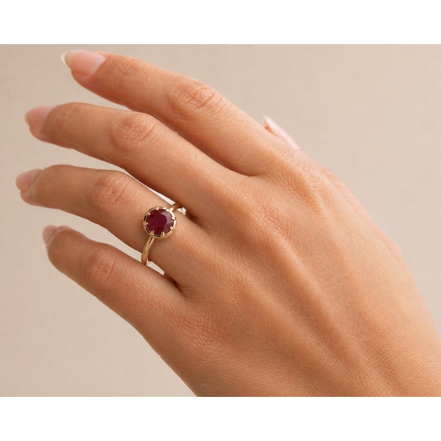 This solitaire ring features a 1.75 carat round-cut natural ruby set in 14K yellow gold. The striking natural ruby in a...