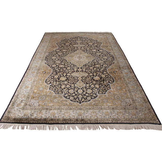 A 7x11 vintage Qum rug in a regal medallion style, enjoying hues of beige-brown atop black with comfortable blue accents....