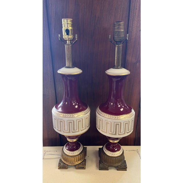 Vintage cream and ox blood red porcelain lamps with gold Greek key scroll. Placed on a 5”x5” bronze ormolu base. In...