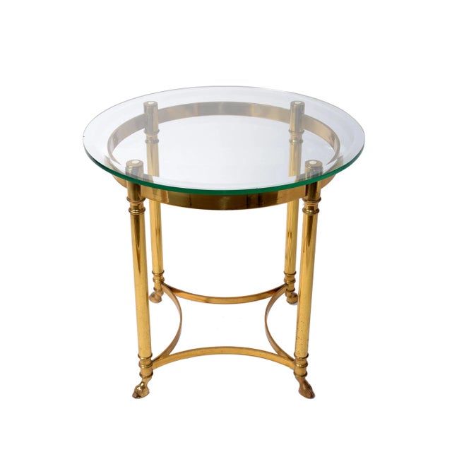 Gorgeous Italian Hollywood Regency brass side table with glass top and hoof feet. Marked at the inside frame. The glass...