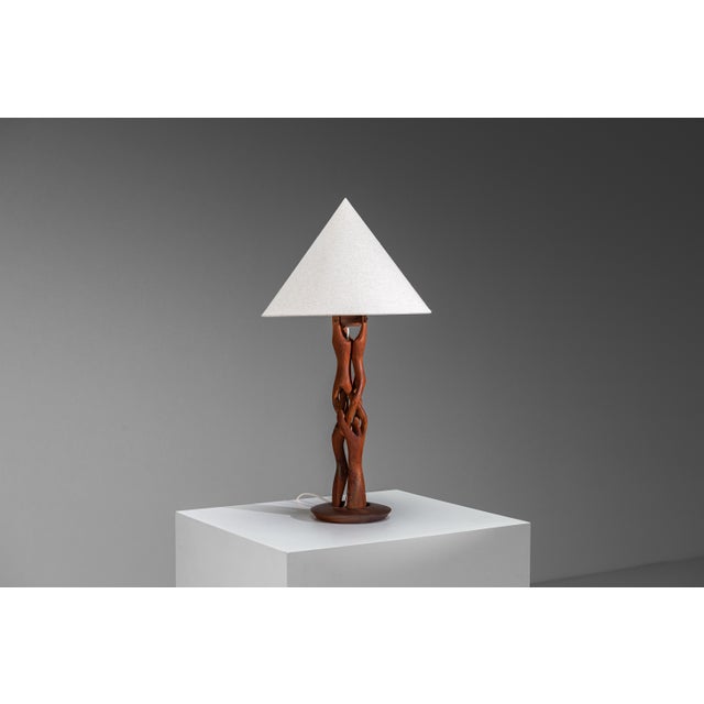 This sculptural teak table lamp is a striking expression of organic design, where functional lighting meets the beauty of...