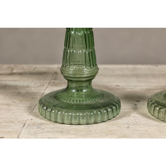 A near pair of green glass gas lights with meander friezes. Discover the unique charm and historical allure of this near...