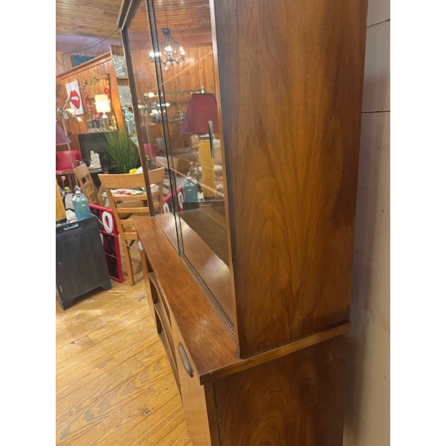 MCM Walnut China Cabinet featuring a lower credenza base and an upper display cabinet with sliding glass doors. It...