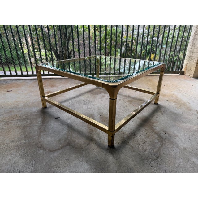 Stylish vintage Hollywood Regency style circa 1970s Mastercraft brass and glass coffee table. Has a square beveled glass...