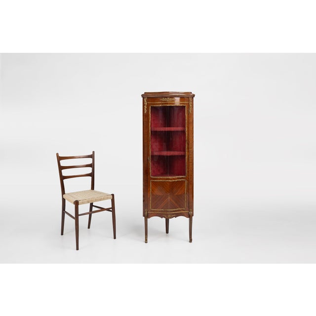A refined French corner display cabinet crafted in the Louis XV style, dating from around 1950. The piece features a...