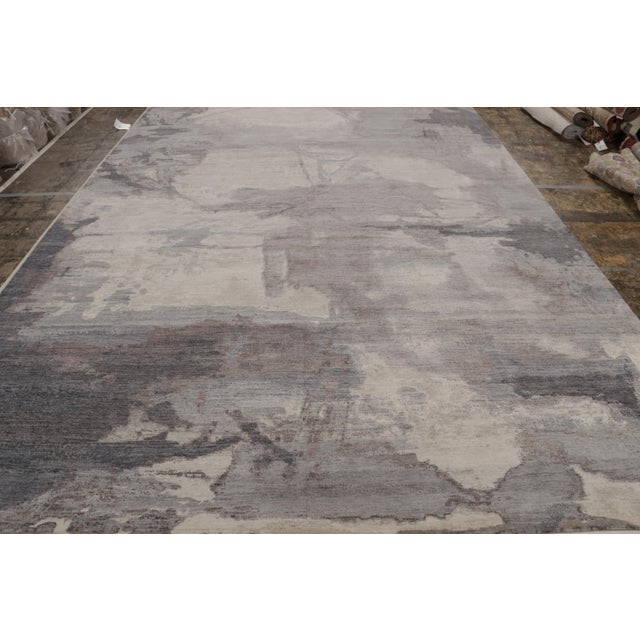 Hand-knotted in wool, this 10x14 modern oversized rug, originating from India, featuring watercolor-like fluid abstract...
