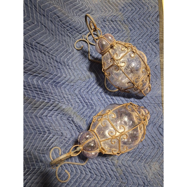 A striking pair of Mediterranean lantern sconces featuring hand-forged wrought iron frames and beautifully textured...