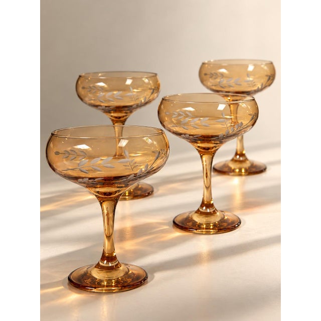 Classy and elegant set of smoked amber champagne coupe glasses featuring beautifully etched detailing throughout. The warm...