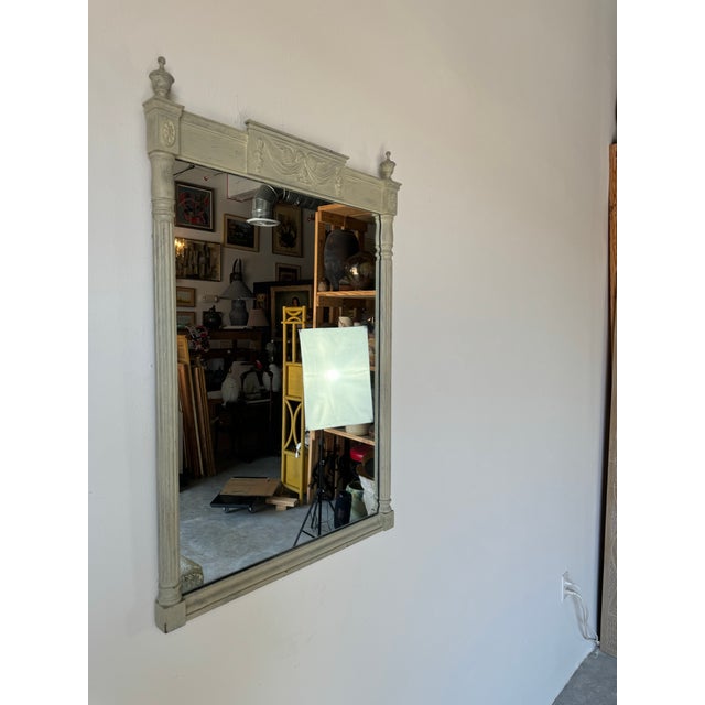 A gorgeous Vintage Neoclassical or Louis XVI style carved wood wall mirror, painted in a distressed finish. A hanging wire...