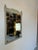 A gorgeous Vintage Neoclassical or Louis XVI style carved wood wall mirror, painted in a distressed finish. A hanging wire...