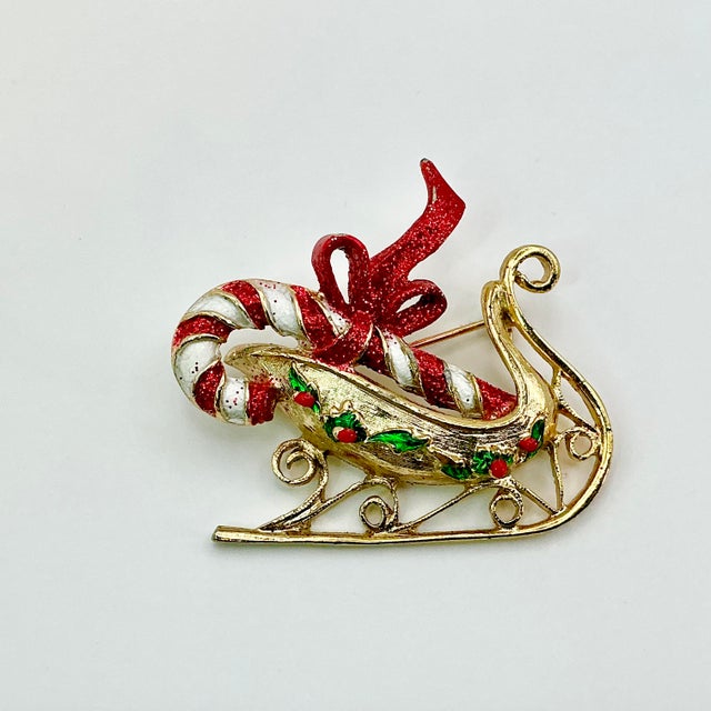 A lovely Christmas Brooch from the 1960s. It features a gold tone Santa Sleigh with green holly and red berries accent. In...