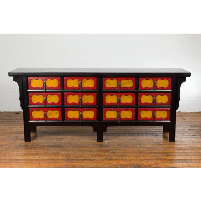 A Chinese Qing Dynasty period long sideboard from the 19th century with black lacquer structure, 12 drawers adorned with...