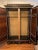 A stunning Spanish armoire featuring elaborate marquetry panels set in a black frame with brass accents. The panels are...