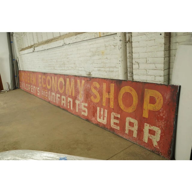 Reclaimed movie set sign made of aluminum in yellow, red, and white colors. The sign reads "Modern Economy Shop,...