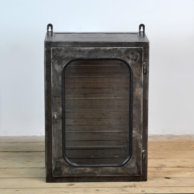 Vintage medicine cabinet from the 1970s, produced in Hungary. The cabinet is made of iron and glass, with the glass held...