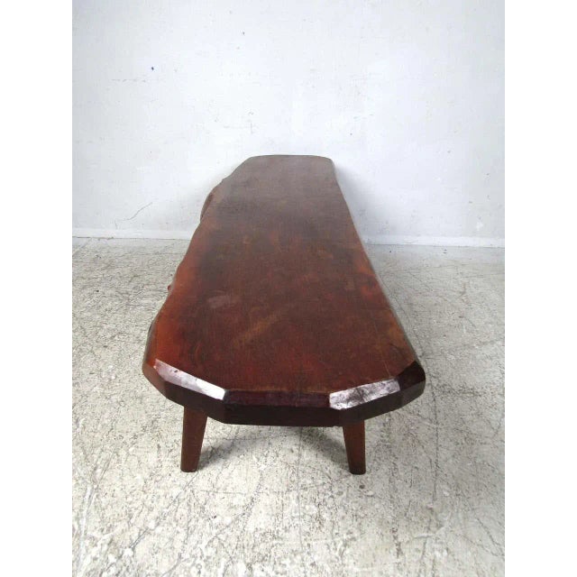 Rustic tree-slab coffee table. Live edge design, with a planned surface covered in a dark finish. Splayed legs support the...