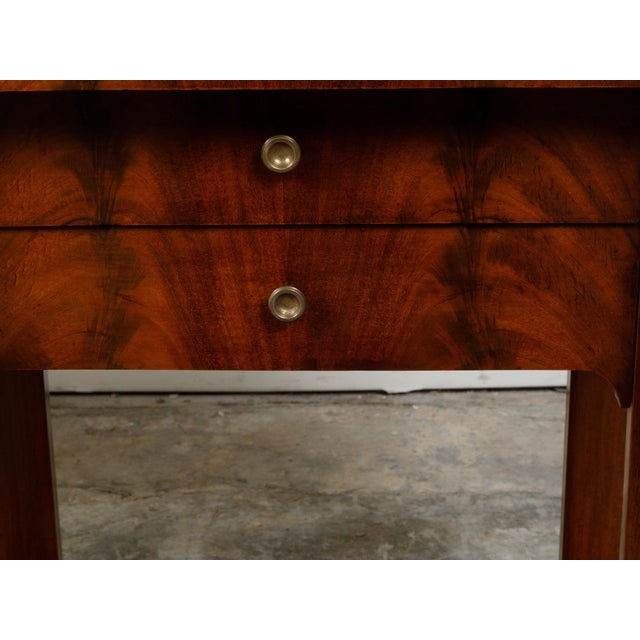 A pair of French Empire period walnut veneered console tables from the early 19th century, with dark grey marble tops,...