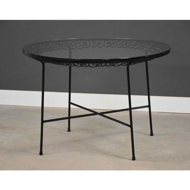 A mid century round dining table with a glass top designed by Arthur Umanoff. Glass has some scratches but no chips. Circa...