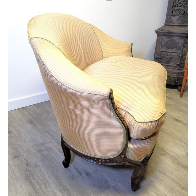 A graceful antique French Louis XV style settee featuring a solid walnut frame with flowing serpentine lines, cabriole...