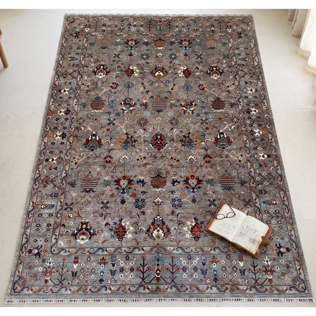 A hand-knotted area rug in the Sultanabad design, woven in Afghanistan on a warm taupe-grey ground and drawn with rows of...