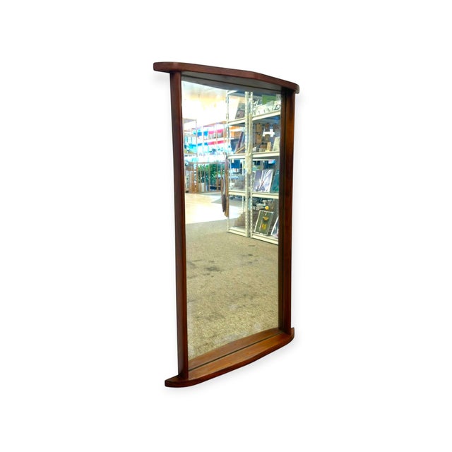 This vertical wall mirror features a rich dark wood frame highlighted by distinct, gently curved top and bottom ledge caps...