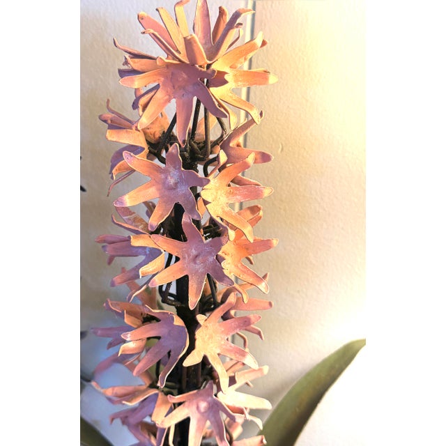A charming vintage tole hyacinth sculpture featuring layered hand-formed metal blossoms in a soft pink tone rising above...
