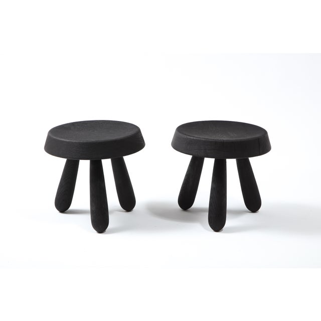 Pair of beautifully crafted petite tripod stools by French designer Douglas Mont. A thick beveled seat sits on three...