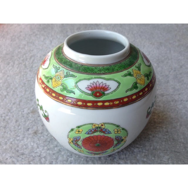 This vintage Chinese enameled porcelain ginger jar measures 5 1/4" tall and features a green floral and butterfly motif....