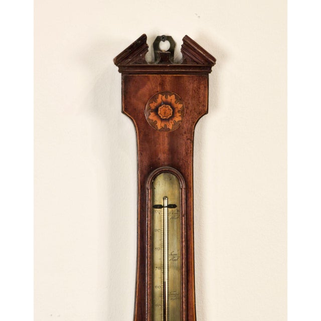 An early 19th-century banjo barometer with pediment and elaborate inlay.