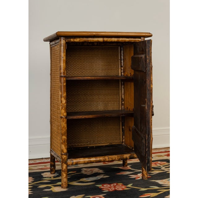 Late Victorian tortoiseshell bamboo single-door cabinet with woven rattan panel door and original hardware. Pine back,...