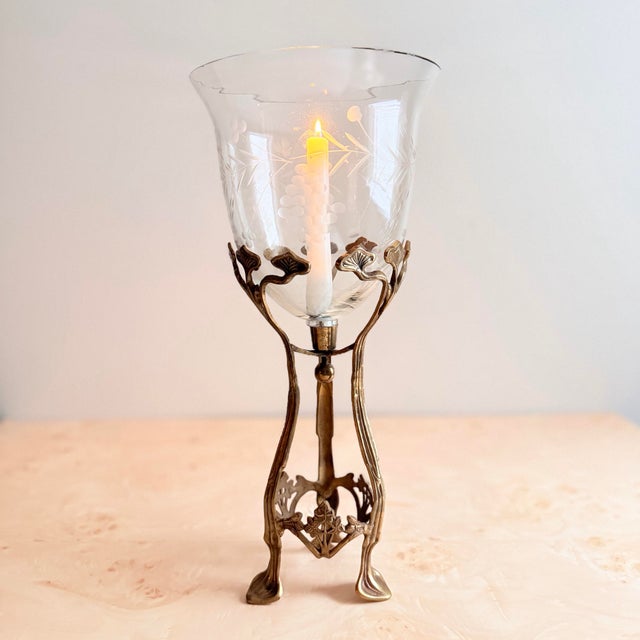 A genuinely rare and museum-quality Art Nouveau object — a brass tripod hurricane candleholder with its original hand-...